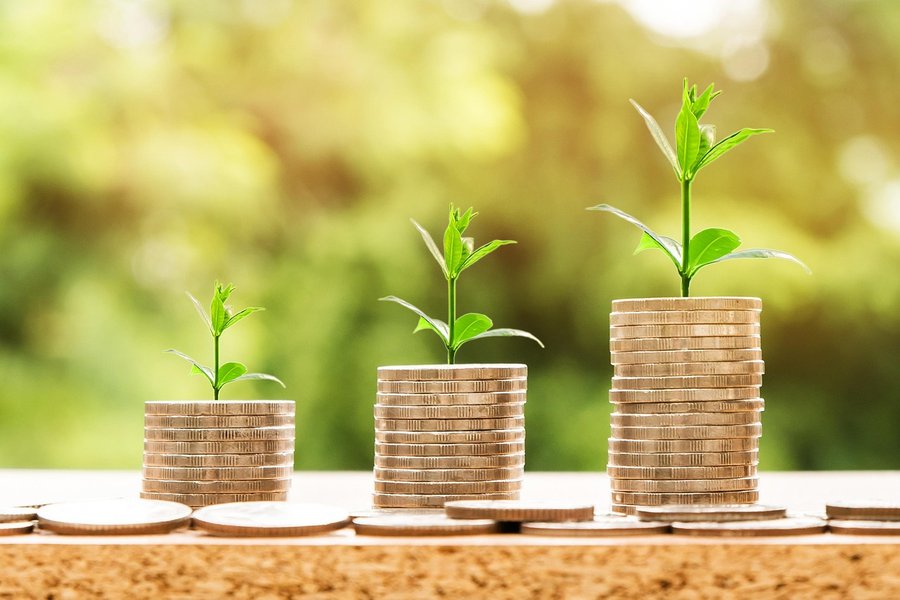 Trois piles de pièces d'or croissantes surmontées de jeunes pousses vertes expliquant comment booster son score de crédit algorithmique pour obtenir un financement immédiat.