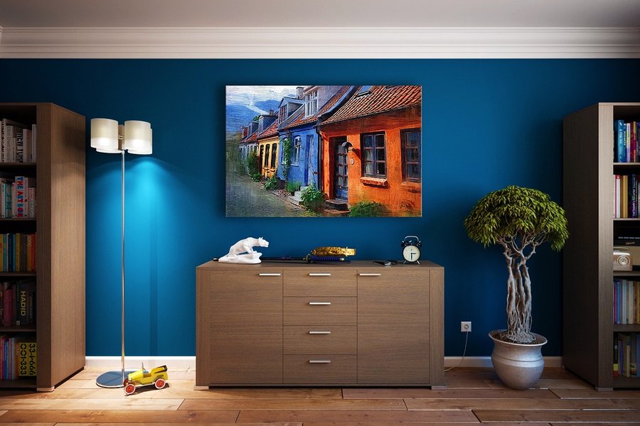 Un salon moderne et chaleureux montrant comment isoler une pièce du froid avec une simple peinture thermique appliquée sur un grand mur bleu profond.
