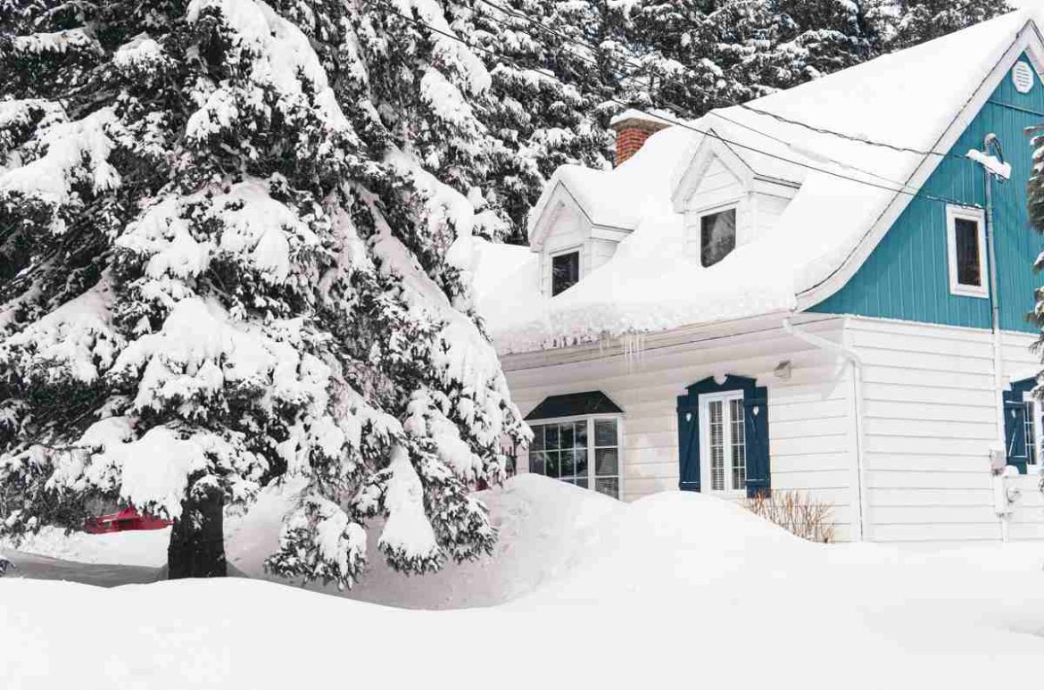 Une grande maison traditionnelle recouverte de neige au cœur de l'hiver, illustrant l'importance de trouver quel est le chauffage le plus économique pour grande maison