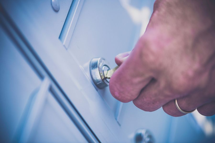 Une main insère une clé dans une serrure de boîte aux lettres blanche, illustrant le problème lorsqu'une serrure de boîte aux lettres ne s'ouvre pas avec la clé d'origine.